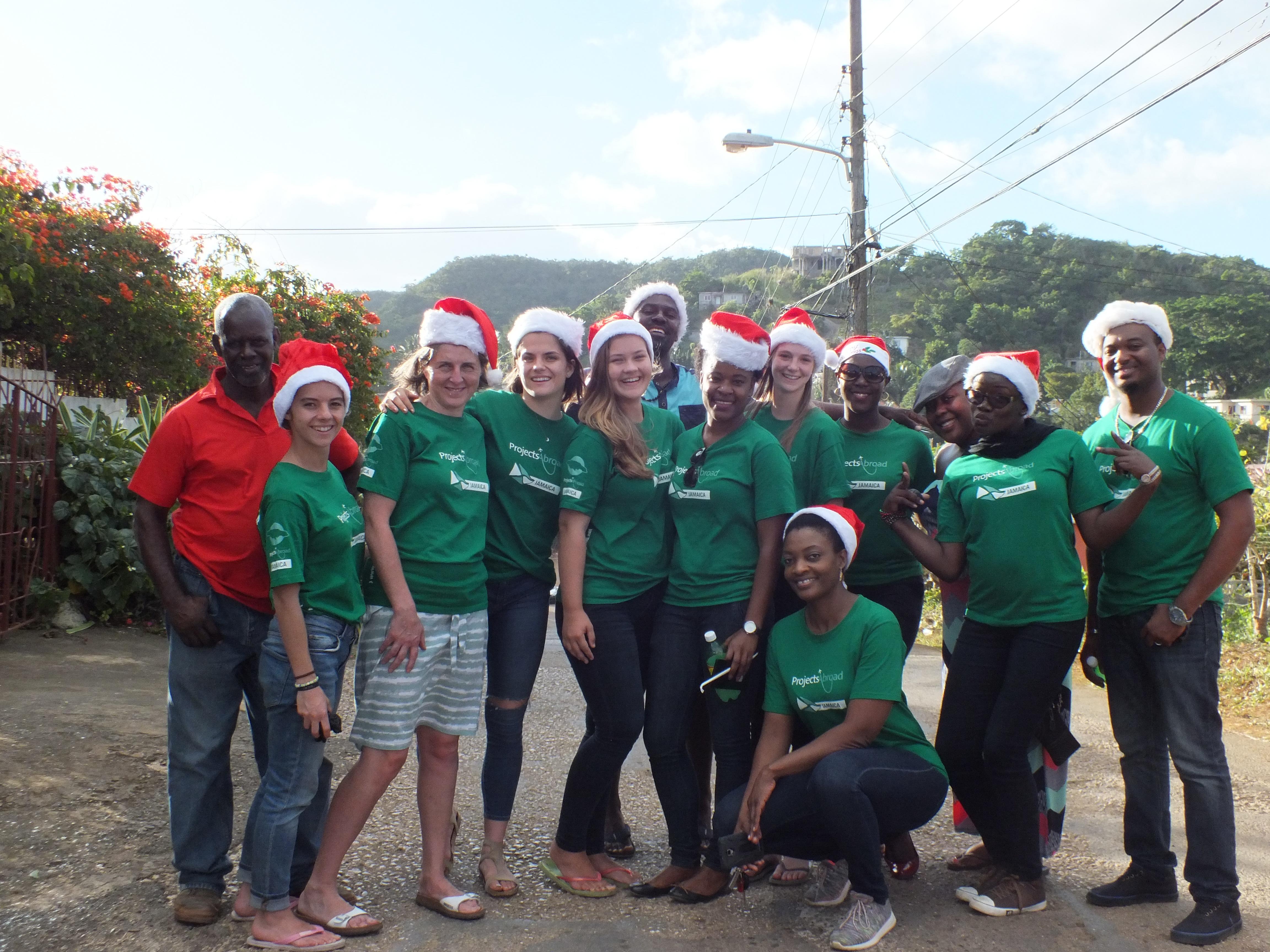 Projects Abroad high school student volunteers working with children, take a group photo with supervisors at a Christmas party for children. Volunteers working with children at a Summer Camp in Jamaica, take a photo with their supervisors outside their placement.